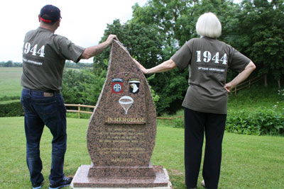 Dennis Keesee and Paula Prindle on either side of the memorial at La Fière, Normandy. It reads, “In peace, sons bury their fathers. In war, fathers bury their sons.” — Herodotus