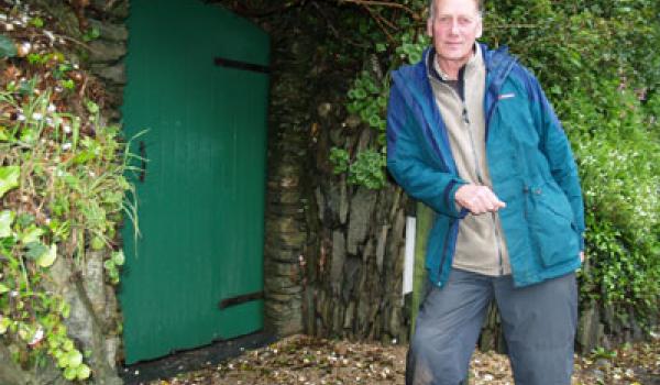 Sir Geoffrey standing near the green door to the Secret Seaside Gardens of Black